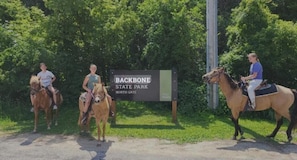 Schild für den North Gate des Backbone State Park, drei Personen auf Pferden.