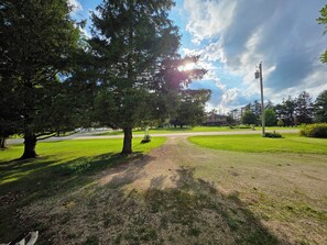 Ein Park mit einem Feldweg, Bäumen und einem Gebäude im Hintergrund.
