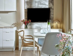 A modern kitchen with a flat-screen TV, white cabinetry, and a dining area with a chair and table. - Comfortable 2-room Apartments Close to the Beach (Mielno)