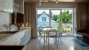 Een moderne keuken met een eethoek, grote ramen en uitzicht op een huis.