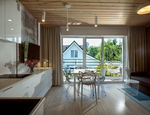 A modern kitchen with a dining area, large windows, and a view of a house. - Comfortable 2-room Apartments Close to the Beach (Mielno)