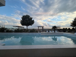 A swimming pool with lounge chairs, a pergola, and a large tree. - Bright apartment in brilliant Dallas with AC and fitness room (Dallas)