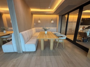 A modern interior with a wooden dining table, cushioned seating, and vertical wooden slats on the walls. - Bright apartment in brilliant Dallas with AC and fitness room (Dallas)
