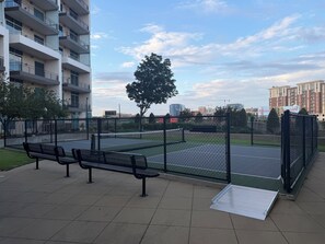 A sports court with a fence, benches, and a tree. - Bright apartment in brilliant Dallas with AC and fitness room (Dallas)