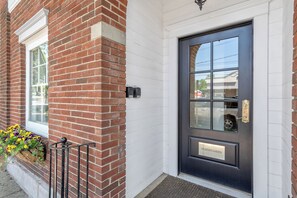 A brick building with a black door labeled 'HEATON'S HAVEN' and a window with a flower box. - Heaton's Haven Suite B - Lovely apartment with king bed in a great location! (Baldwinsville)