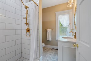 A bathroom with a shower, toilet, sink, and window. - Heaton's Haven Suite B - Lovely apartment with king bed in a great location! (Baldwinsville)