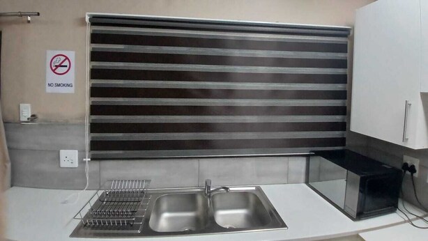 A modern kitchen with a stainless steel sink, a no-smoking sign, and a ventilation hood.