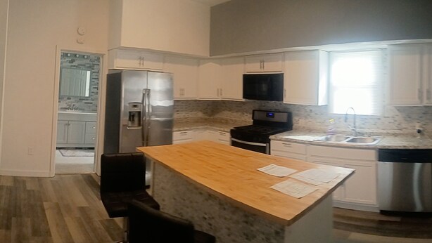 A modern kitchen with a central island, stainless steel appliances, and a window providing natural light.