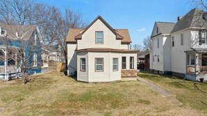A two-story house with a gabled roof, a front porch, and a small front yard.