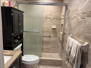 Ein Badezimmer mit Toilette, Duschkabine, Waschtisch mit Spiegel und Handtuchhalter.