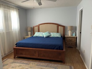 Ein Schlafzimmer mit einem hölzernen Bett, zwei Nachttischen mit Lampen, einem Deckenventilator und einem gemusterten Teppich.