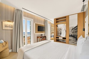 Ein Hotelzimmer mit Bett, Fernseher, Schreibtisch und Meerblick.