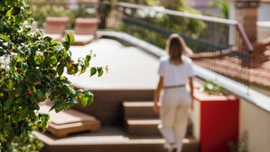 A person walking down a staircase with a railing on one side and a red planter on the other.