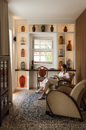 A room with a bookshelf, a window, a chair, and a rug.