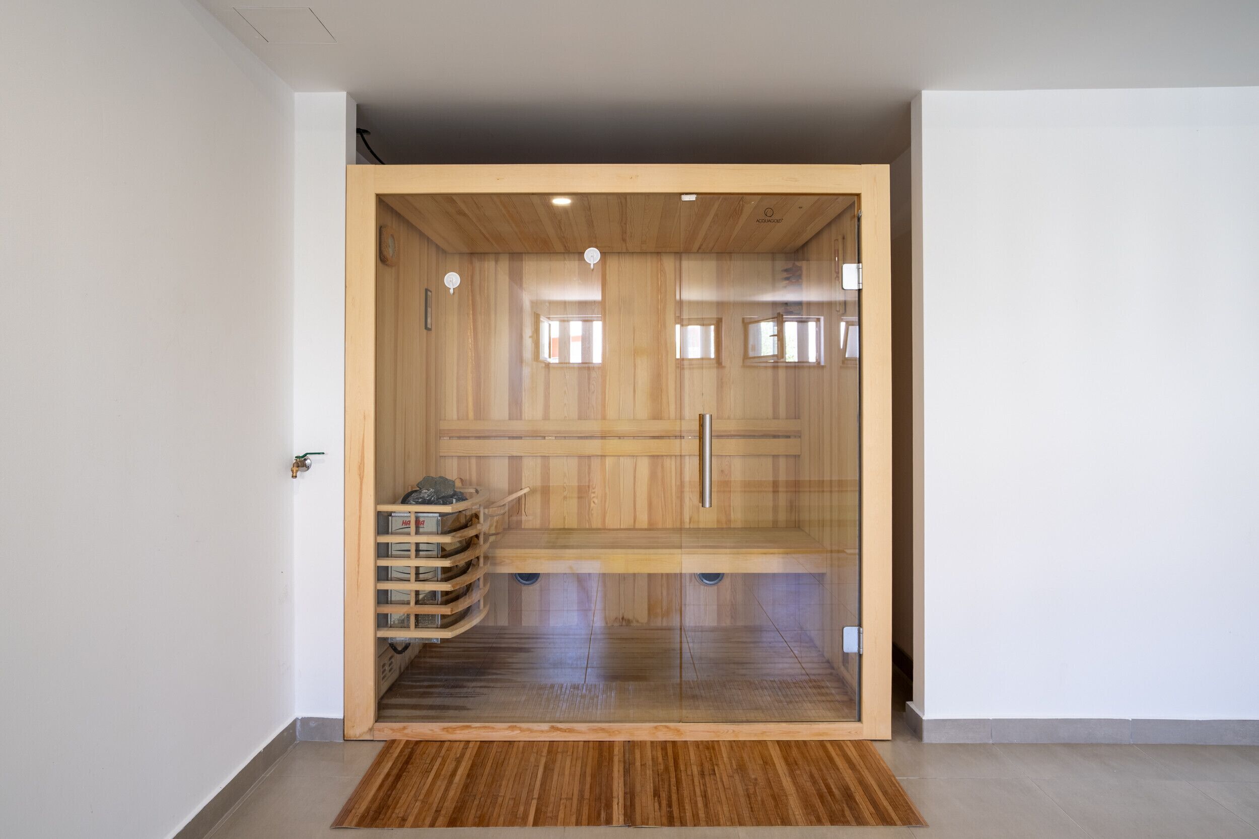Una sala de sauna con paredes de madera, un banco y un estante con objetos.