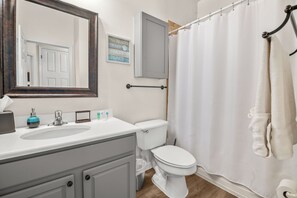 Ein Badezimmer mit weißem Waschbecken, Spiegel, Toilette und Duschvorhang.