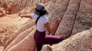 Una persona de pie en un paisaje natural con una gran formación rocosa.