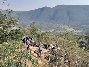 Un grupo de personas en una ladera rocosa con montañas al fondo.