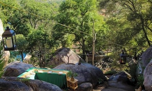 A dining area with a table set for four, surrounded by large rocks and greenery.