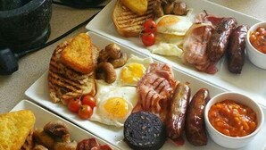 Un plato de desayuno con huevos, salchichas, champiñones y tostadas.