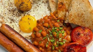 Un plato de comida con huevos, salchichas, frijoles, champiñones y tostadas.