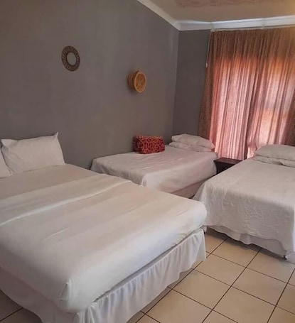 A hotel room with three beds, a small table, and a curtain.. Tfutjana Mount resort and restaurant