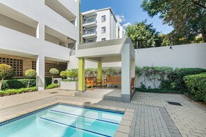 Um edifício moderno com piscina, área de estar ao ar livre e vegetação.