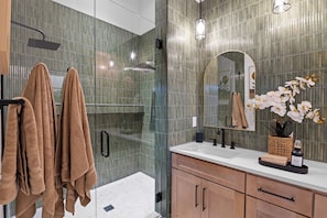 Une salle de bain moderne avec une douche à parois de verre, un lavabo avec un miroir et un porte-serviettes avec des serviettes.