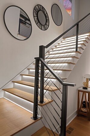 Un escalier avec des marches en bois et des rampes noires, entouré de miroirs fixés aux murs.