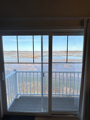 Una habitación con vista a una playa a través de una puerta corrediza de vidrio.