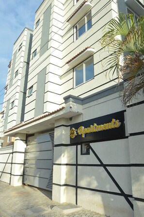 Ein mehrstöckiges Gebäude mit einem Schild für 'Apartments' und einer Palme davor.