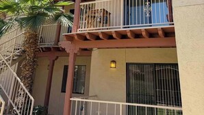 Un edificio de varios pisos con balcones, una palmera y una escalera.