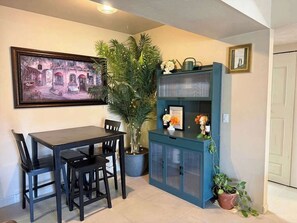 A dining area with a table and chairs, a potted plant, a cabinet with glass doors, and a framed picture on the wall. - Quiet Tucson Hideout +pool +patio (Tucson)