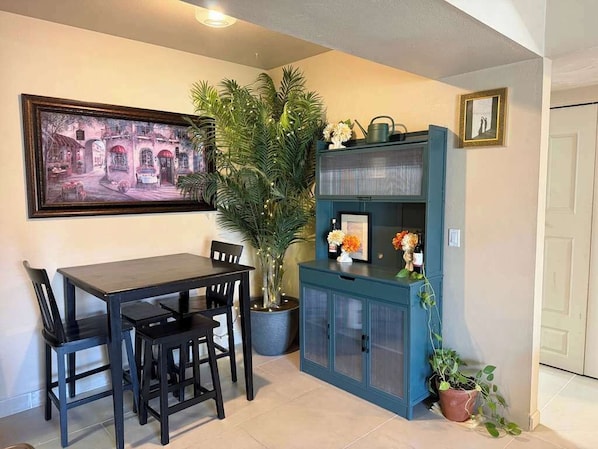 A dining area with a table and chairs, a potted plant, a cabinet with glass doors, and a framed picture on the wall. - Quiet Tucson Hideout +pool +patio (Tucson)