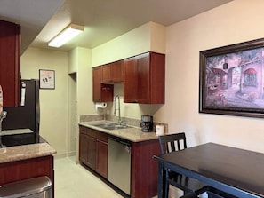 A compact kitchen with a dishwasher, a sink, and a dining area with a table and chairs. - Quiet Tucson Hideout +pool +patio (Tucson)