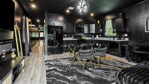 Une cuisine moderne avec un îlot central, des meubles de couleur sombre et un lustre.
