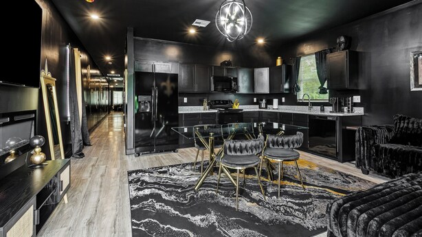 Une cuisine moderne avec un îlot central, des meubles de couleur sombre et un lustre.
