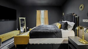 Une chambre à coucher moderne avec un lit, une table de chevet, une lampe, un banc et un miroir.