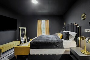 Ein modernes Schlafzimmer mit Bett, Nachttisch, Lampe, Bank und Spiegel.