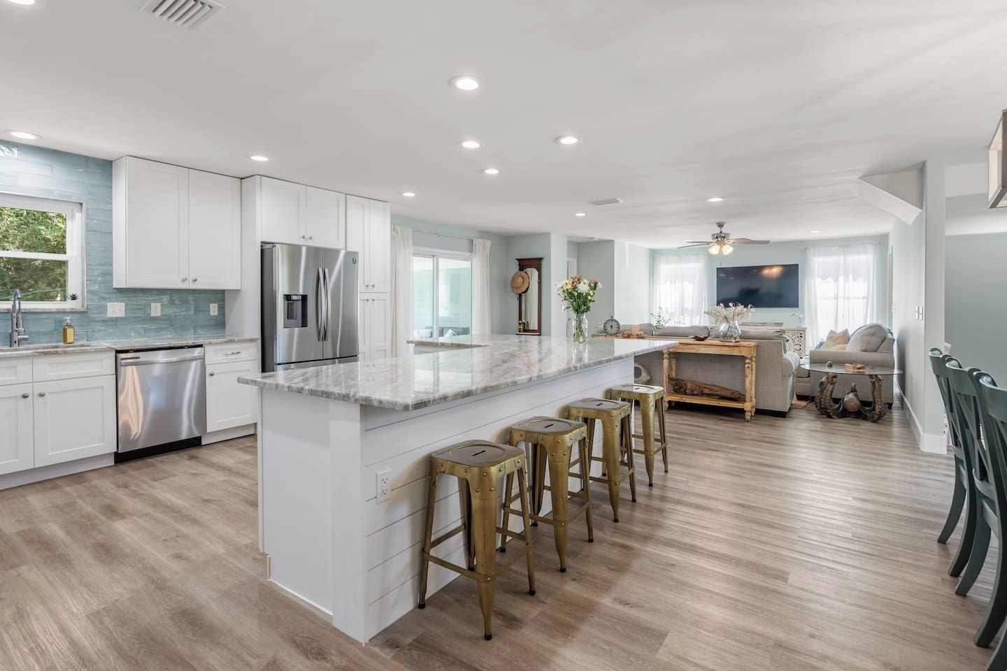 A modern kitchen with white cabinets, stainless steel appliances, and a marble countertop.