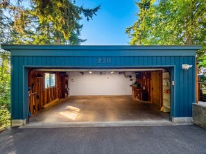 A blue garage with the number 230, wooden interior, and a concrete floor. - Luxury Treehouse Retreat | Hot Tub + Bay Views (Bellingham)