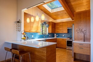 A modern kitchen with wooden cabinetry, a large island, and a skylight.