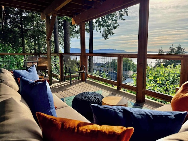 A covered outdoor seating area with a view of a lake and mountains.