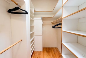 A walk-in closet with wooden flooring, white walls, and multiple shelves. - Luxury Treehouse Retreat | Hot Tub + Bay Views (Bellingham)