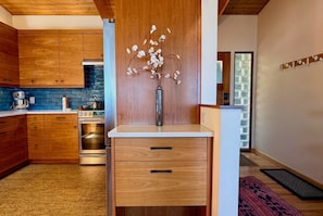 Una cocina moderna con armarios de madera, un horno de acero inoxidable y un florero con flores en la encimera.