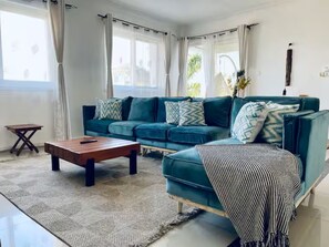 A living room with a teal sofa, a wooden coffee table, and a striped throw blanket. - Lovely 3-bedroom apartment near the beach (Dar es Salaam)