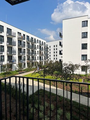 Un edificio de apartamentos moderno con balcones, un patio central y cielo despejado.
