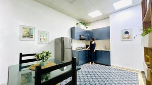 Eine moderne Küche mit Essbereich, ausgestattet mit einem Kühlschrank, Herd und blau gemustertem Boden.