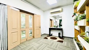 Ein Zimmer mit großem Kleiderschrank, Spiegel, Schreibtisch und einer Pflanzenablage.