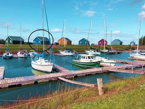 Un puerto deportivo con barcos amarrados, muelles de madera y varias casas pequeñas al fondo.